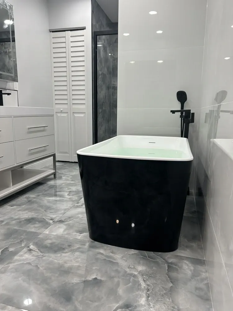 Gray veined-tile bathroom with black freestanding tub