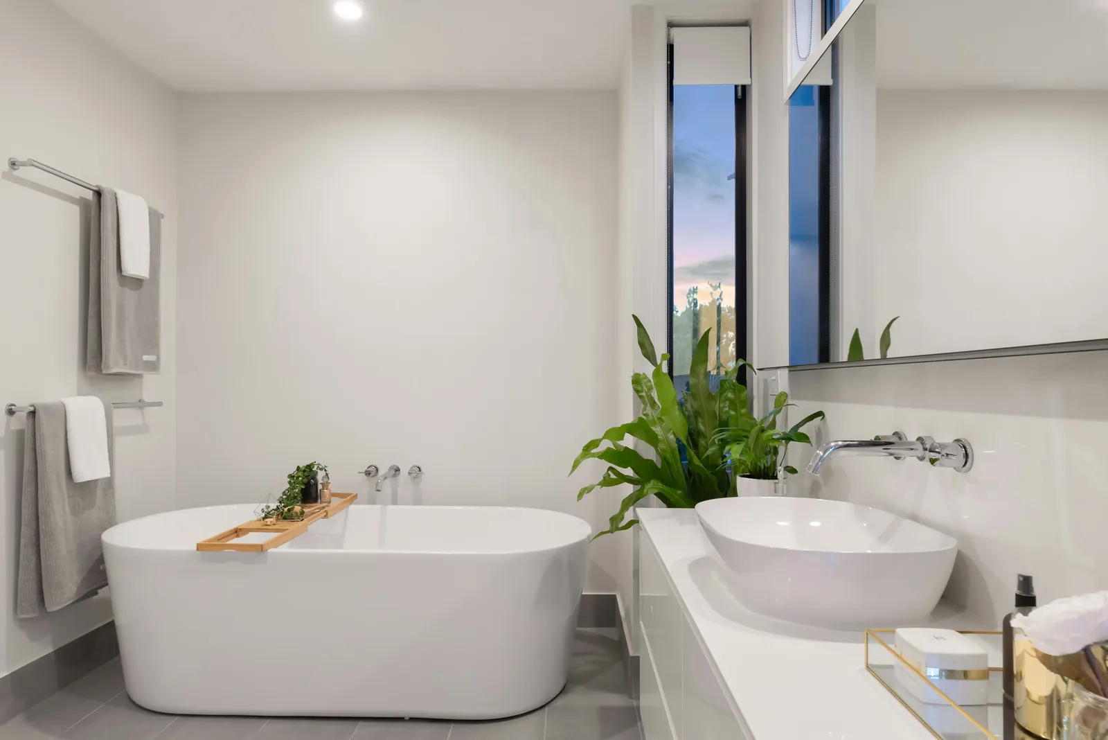 White bathroom with gray floor tiles and a narrow window