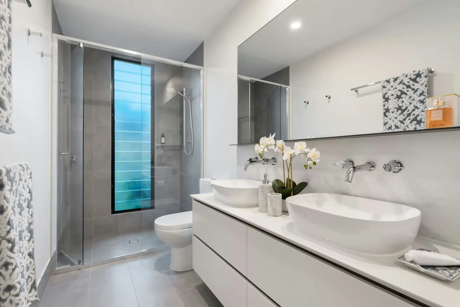 White bathroom with gray floor tiles and a narrow window